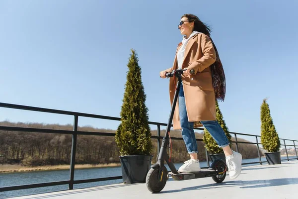 Fiatal Gyönyörű Kabátban Mosolyog Elektromos Robogóval Jár Irodaházakba Dolgozni — Stock Fotó