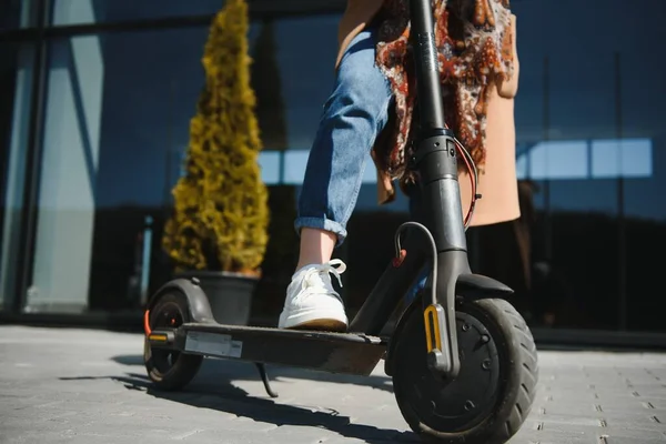 街中で黒い電動キックスクーターに乗っている女性のクローズアップ モーションブラー — ストック写真