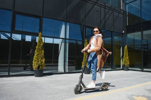 Fiatal Gyönyörű Kabátban Mosolyog Elektromos Robogóval Jár Irodaházakba Dolgozni — Stock Fotó