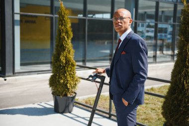 Dışarıda elektrikli scooter sürerken gülümseyen 30 'lu yaşlarda yakışıklı bir Afrikalı.