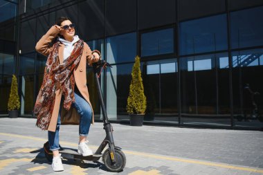 İşe elektrikli scooterla giden genç, güzel bir kadın, modern kız, yeni nesil, elektrik nakli, ekolojik ulaşım, ekolojik ulaşım, gün batımı