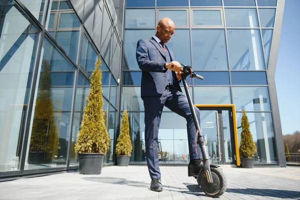 Geschäftsmann Mit Elektroroller Steht Vor Modernem Geschäftshaus Und Telefoniert — Stockfoto