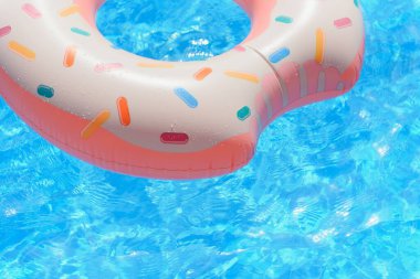 Yüzme havuzunda pembe şişme donut yüzme yüzüğü.