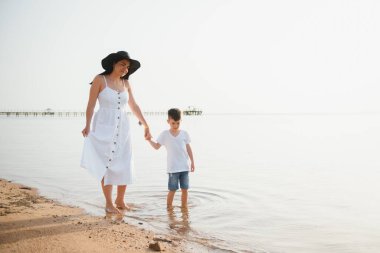 Anne ve oğlu gündüz vakti plajda oynuyorlar. Arkadaş canlısı aile kavramı.