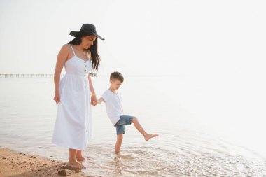 Anne ve oğlu gündüz vakti plajda oynuyorlar. Arkadaş canlısı aile kavramı.