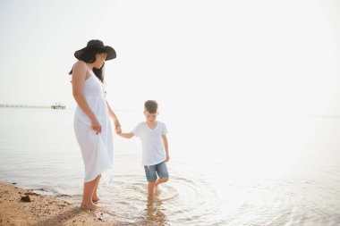 Anne ve oğlu gündüz vakti plajda oynuyorlar. Arkadaş canlısı aile kavramı.