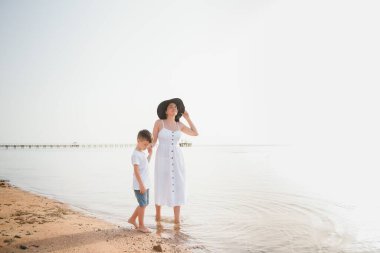 Anne ve oğlu gündüz vakti plajda oynuyorlar. Arkadaş canlısı aile kavramı.