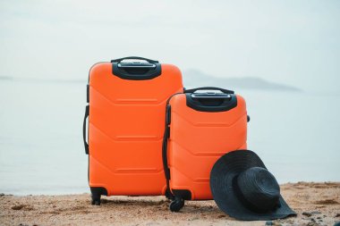 Tatil bavulu, hasır şapka ve kumsal terlikleri güzel kumsalda. Reklam seyahat valizi