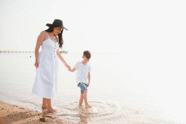 Anne ve oğlu gündüz vakti plajda oynuyorlar. Arkadaş canlısı aile kavramı.