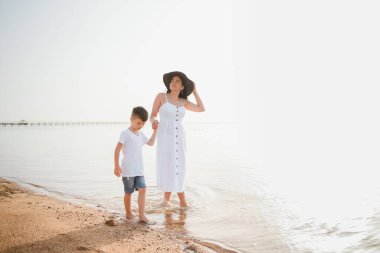 Anne ve oğlu gündüz vakti plajda oynuyorlar. Arkadaş canlısı aile kavramı.