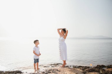 Anne ve oğlu gün batımında sahilde yürüyor.