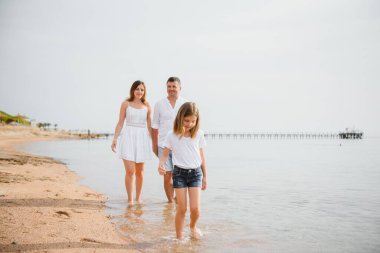 Mutlu bir aile sahilde yürüyor.