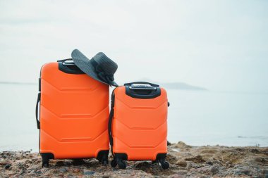 Tatil bavulu, hasır şapka ve kumsal terlikleri güzel kumsalda. Reklam seyahat valizi
