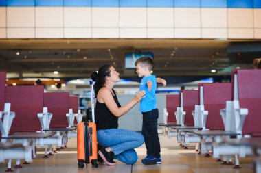 Uçak kalkmadan önce ailesi havaalanında. Anne ve oğlu modern uluslararası terminalin kalkış kapısında binmek için bekliyorlar. Çocuklarla seyahat ve uçmak. Anne ve bebek uçağa biniyor..