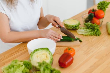 Kadın mutfakta salata yapıyor. Sağlıklı beslenme tarzı konsepti. Mutfakta güzel genç bir kadın yemek pişiriyor..
