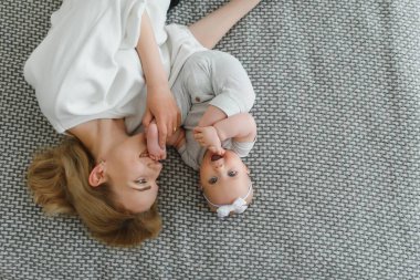 Genç ve mutlu anne, yeni doğmuş bebeğini kucaklıyor. Sabahları yatakta oturuyor..