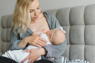 Emzirme konsepti. Genç anne yeni doğmuş bebeğini evde emziriyor.