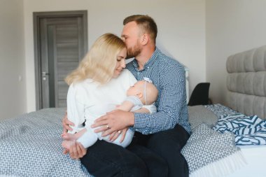 Mutlu ve rahat bir çift kanepede oturup bebeklerine bakıyor.