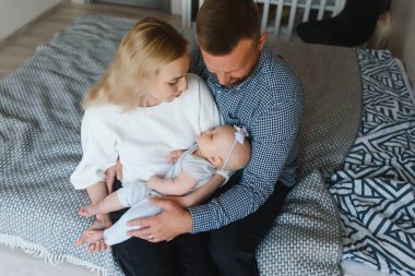 Mutlu ve rahat bir çift kanepede oturup bebeklerine bakıyor.