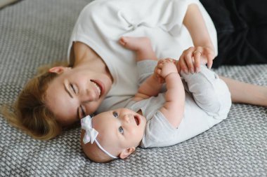 Mutlu gülümseyen anne ve bebek evde yatakta uzanır, üst manzara