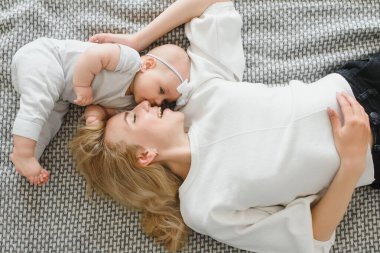 Genç ve mutlu anne, yeni doğmuş bebeğini kucaklıyor. Sabahları yatakta oturuyor..