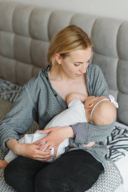 Emzirme konsepti. Genç anne yeni doğmuş bebeğini evde emziriyor.