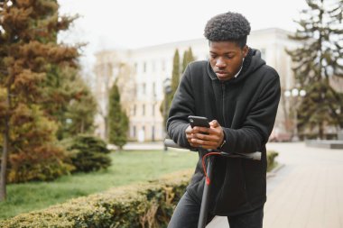 Şehirde elektrikli scooter 'ı olan Afrikalı genç bir Amerikalı. Ekolojik taşıma kavramı.
