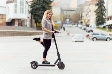 Şehir merkezinde elektrikli scooter kullanan bir kız.
