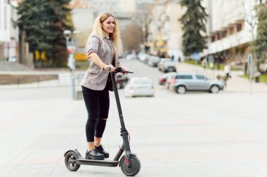 Şehir merkezinde elektrikli scooter kullanan bir kız.