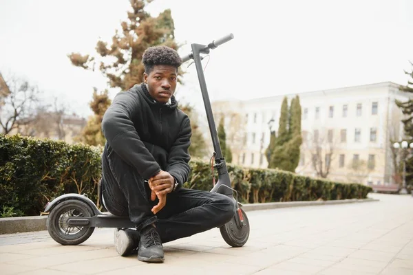 Afroamerikaner Fährt Mit Einem Elektroroller Vor Dem Hintergrund Einer Mauer — Stockfoto