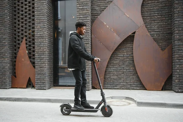 Afro American Guy Rijdt Een Elektrische Scooter Tegen Achtergrond Van — Stockfoto