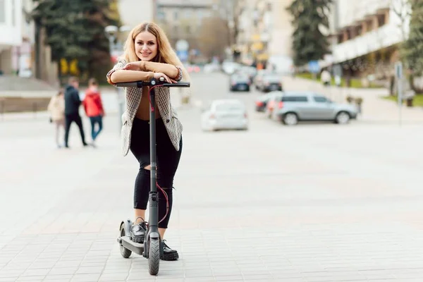 young woman on electro scooter in city. woman riding scooter in sunset light in street