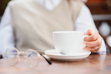 Kadın elleri bir fincan kahve tutuyor.