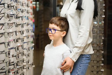 Anne ve oğlu optik dükkanında gözlük seçiyor..