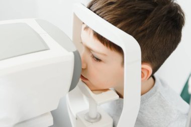 Optimetri kavramı. Kadın optometrist göz doktoru göz muayenehanesindeki çocuğu muayene ediyor.