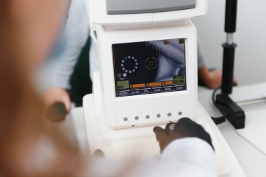 Modern tıbbi ekipmanlar. Çocuk gözlerini incelerken otomatikman kırılma ölçümü kullanarak göz doktorunu kapat