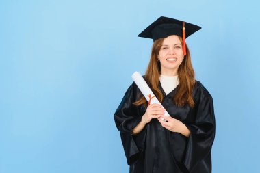 Mavi arka planda mezuniyet şapkası ve cübbesi giyen mezun bir kadın öğrenci.