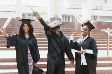 Eğitim, mezuniyet ve halk konsepti. Havan topu ve diplomalı bekarlık elbisesi giyen bir grup mutlu uluslararası öğrenci.