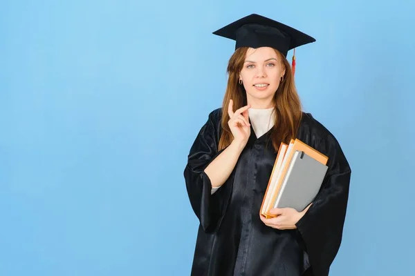 卒業帽子とガウンを身に着けている女性大学院生 青の背景に — ストック写真