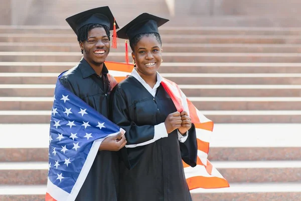 人々のコンセプト モルタルボードとアメリカ国旗の学士号を持つ幸せな留学生 — ストック写真