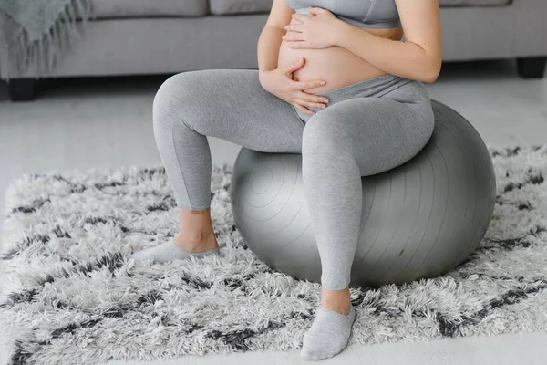 Young pregnant woman exercising yoga with fit ball at home. Healthy sports pregnancy concept