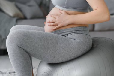 Evde formda bir topla yoga yapan hamile bir kadın. Sağlıklı spor hamileliği kavramı