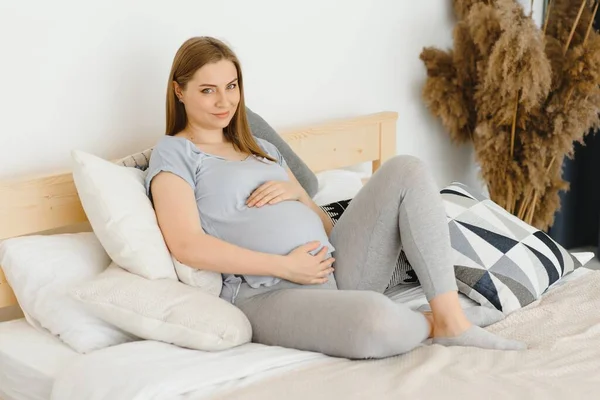 Schwangere Junge Europäerin Sitzt Auf Einem Großen Bett Und Streichelt — Stockfoto