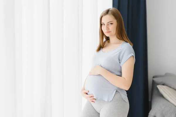 Hermosa Mujer Embarazada Está Tocando Vientre Sonriendo Mientras Está Pie — Foto de Stock
