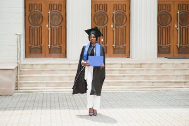 Güzel Afro-Amerikan bayan mezunları üniversite binasının dışında.