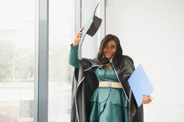 Mezuniyet elbisesi ve şapkası içinde diploması olan mutlu Hintli üniversite öğrencisi. Asya kökenli Hintli ve Afrikalı melez portresi.