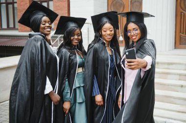 Eğitim, mezuniyet, teknoloji ve insan kavramı - harç panoları ve bekarlığa veda önlük selfie smartphone açık havada tarafından alarak diploma ile mutlu uluslararası öğrenci grubu
