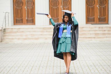 Mezuniyet elbisesi ve şapkası içinde diploması olan mutlu Hintli üniversite öğrencisi. Asya kökenli Hintli ve Afrikalı melez portresi.