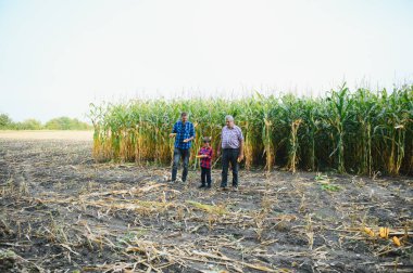 Oğlu ve torunuyla birlikte tarlasında dikilen yaşlı çiftçinin portresi. Aile çiftliği.