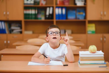 Masada oturan ve arkasında oturan sınıf arkadaşı ile egzersiz yazarak konsantre öğrenci
